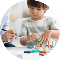 young boy stacking a blue piece on a wooden peg